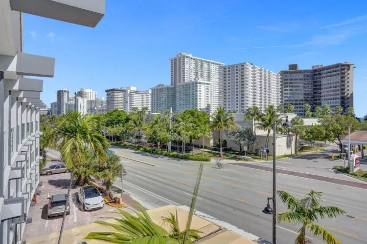Street view of modern hotel buildings with palm trees and traffic