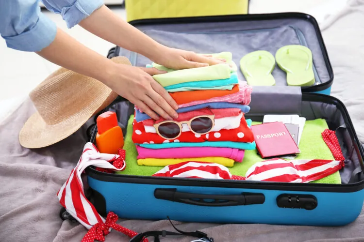 Open suitcase packed with folded clothes and travel accessories