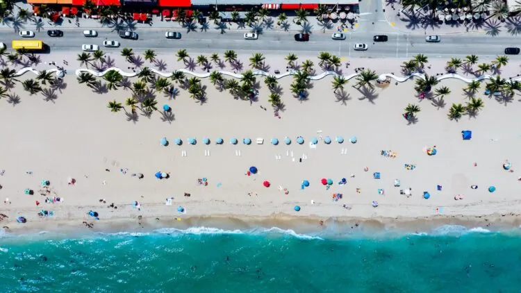 Aerial view of a sandy beach with umbrellas and people along the shoreline