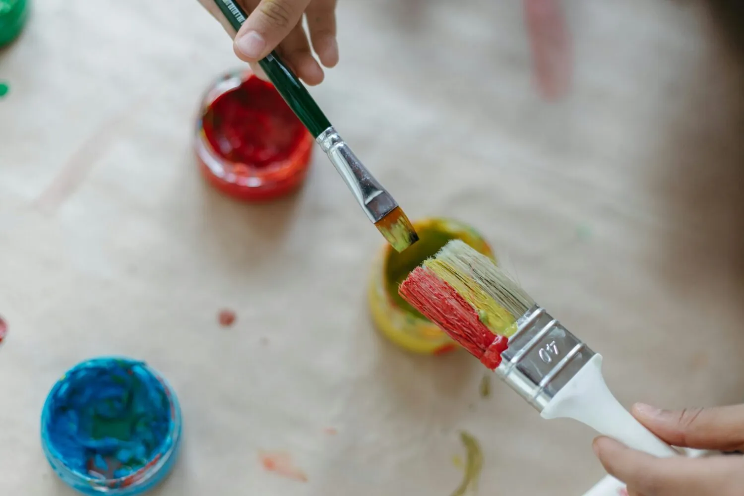 Person painting a small wooden object with bright coloured paint