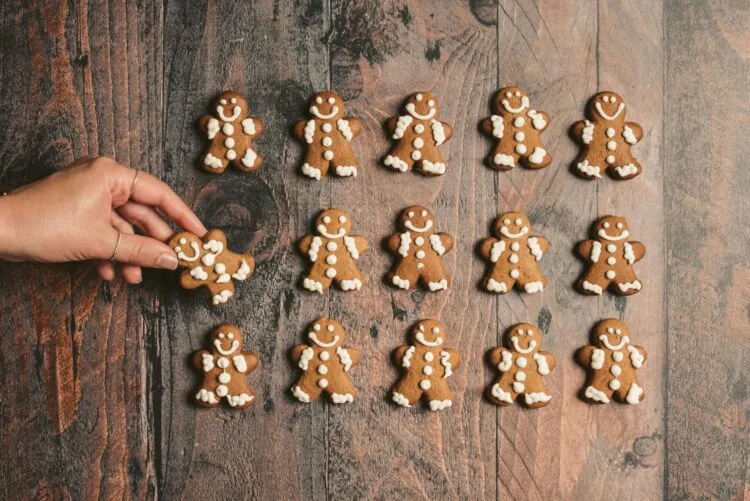 Hand placing gingerbread cookies in neat rows on a wooden table