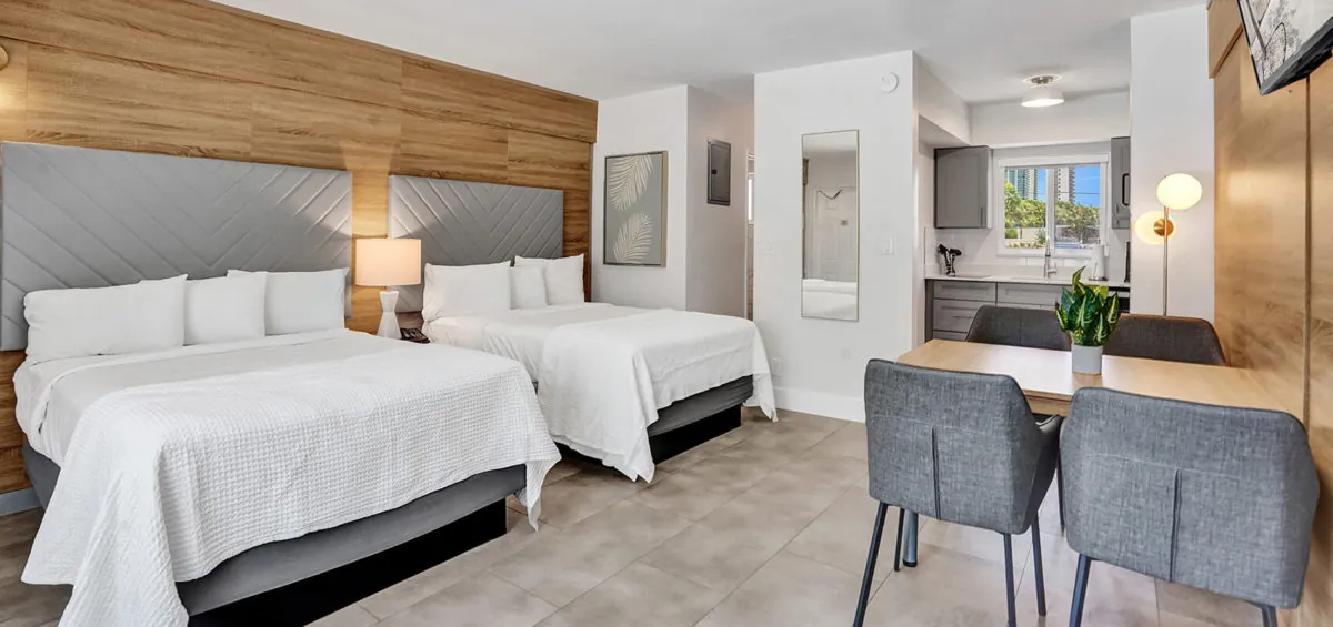 Two queen beds with desk, chairs, and modern hotel room decor