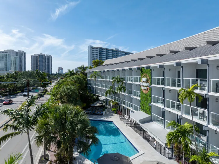 Aerial view of resort pool, palm trees, and surrounding buildings