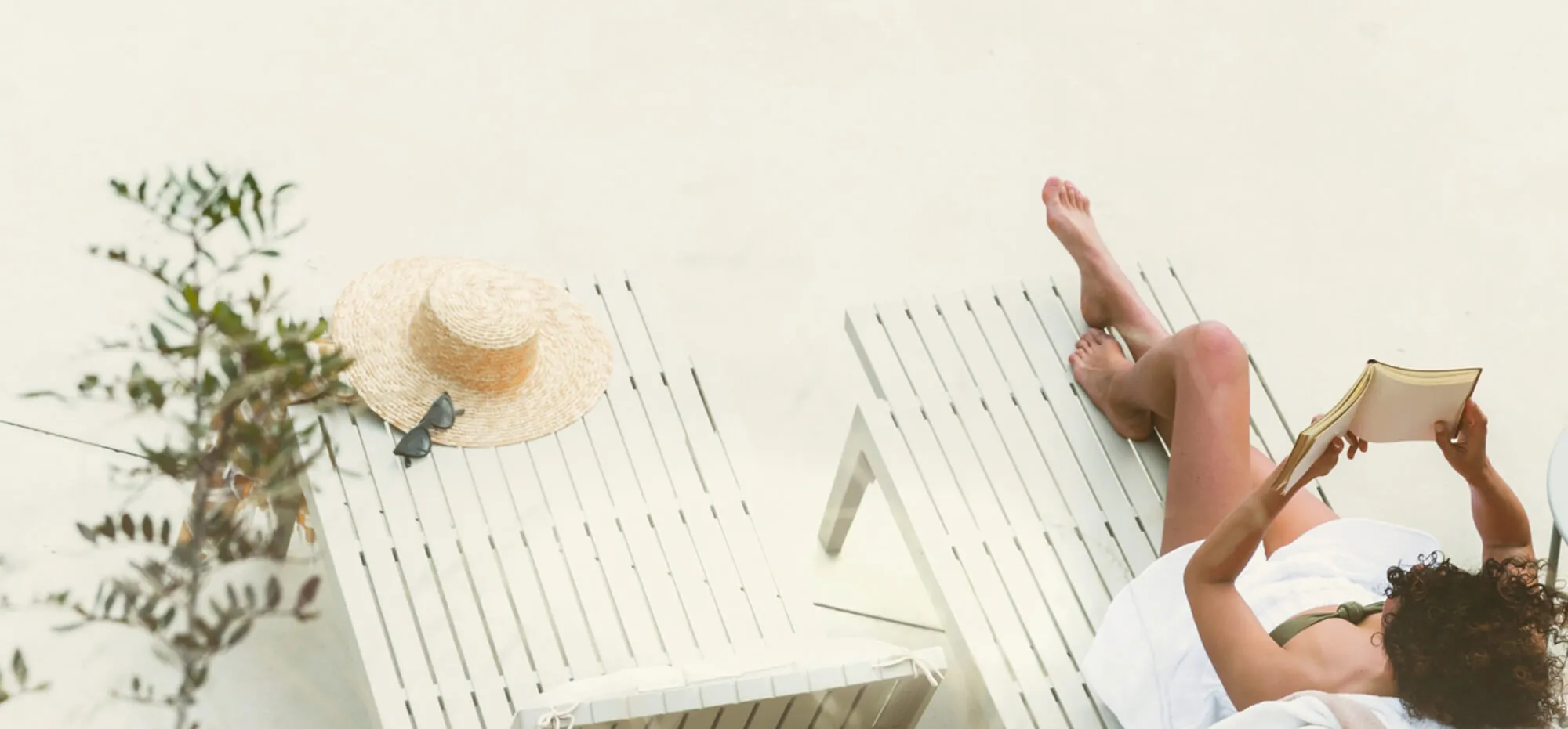 Person relaxing on a sun lounger reading a book on a terrace