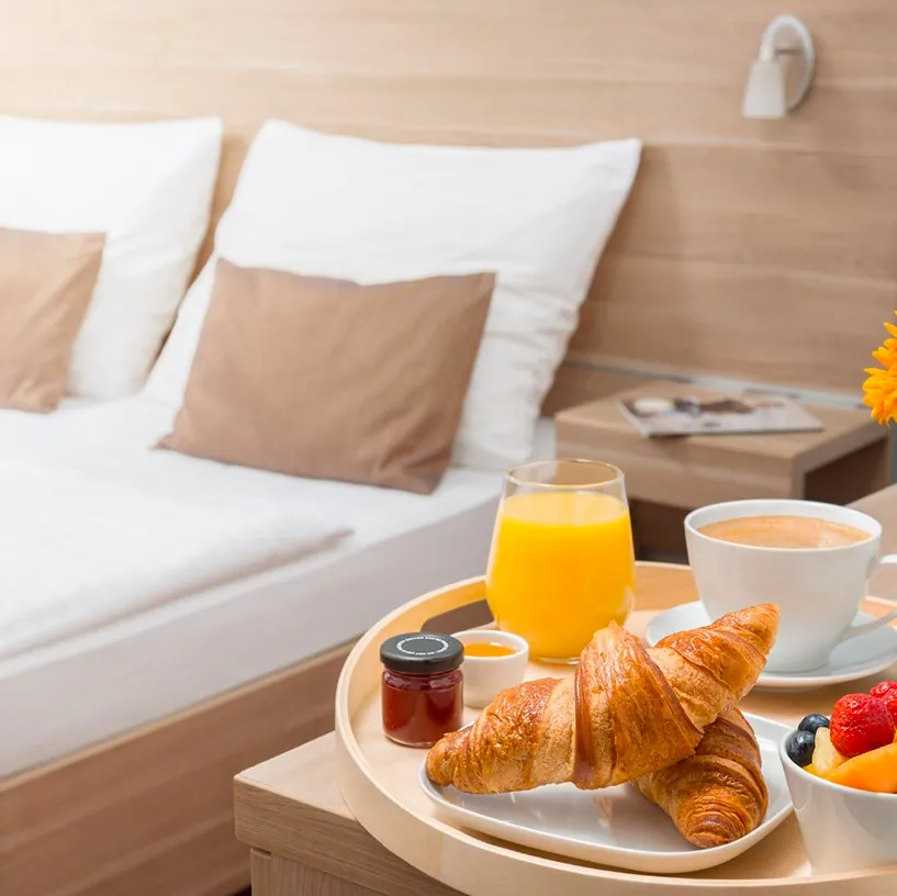 In-room dining tray with croissant, orange juice, coffee, and fruit