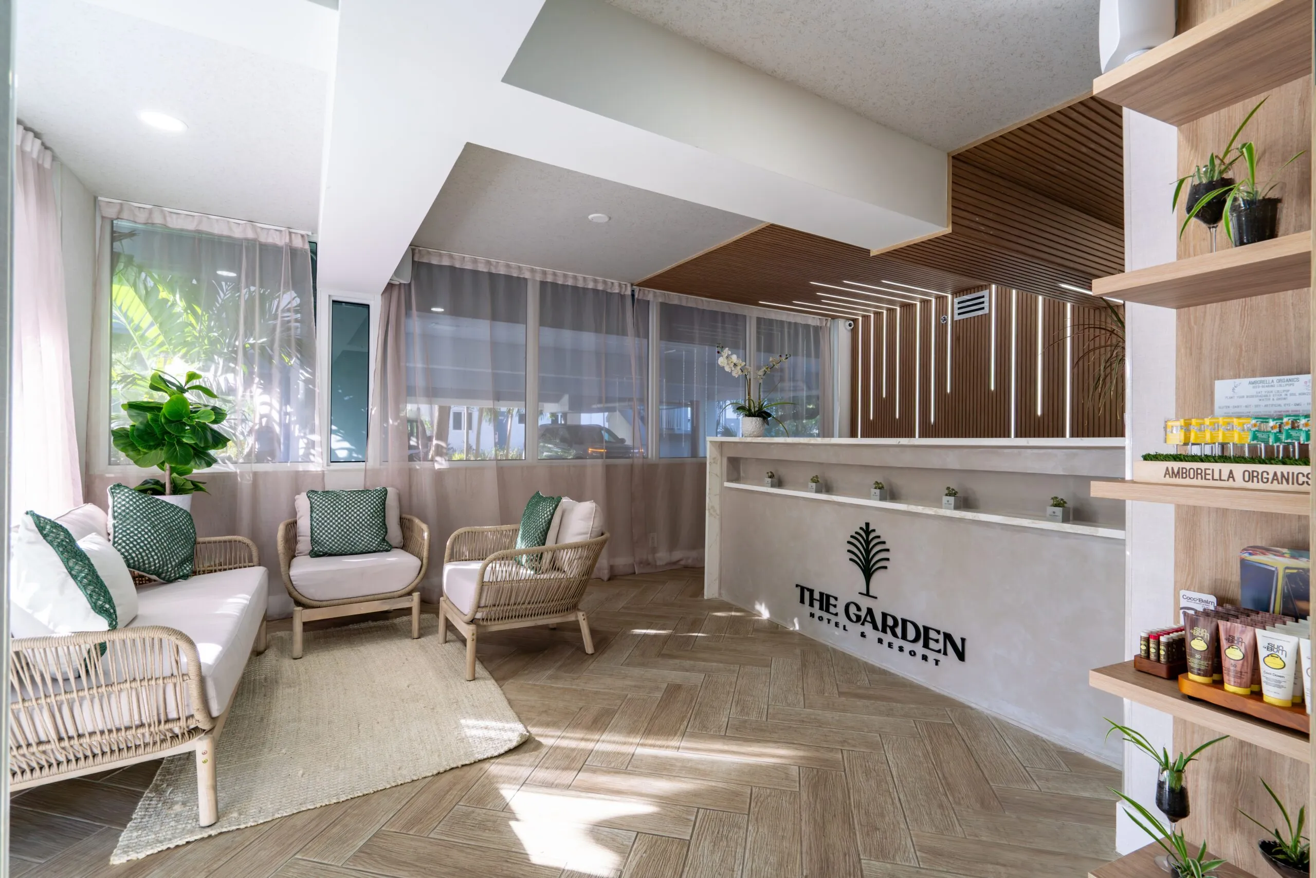 Bright hotel lobby with reception desk, seating, and retail shelves