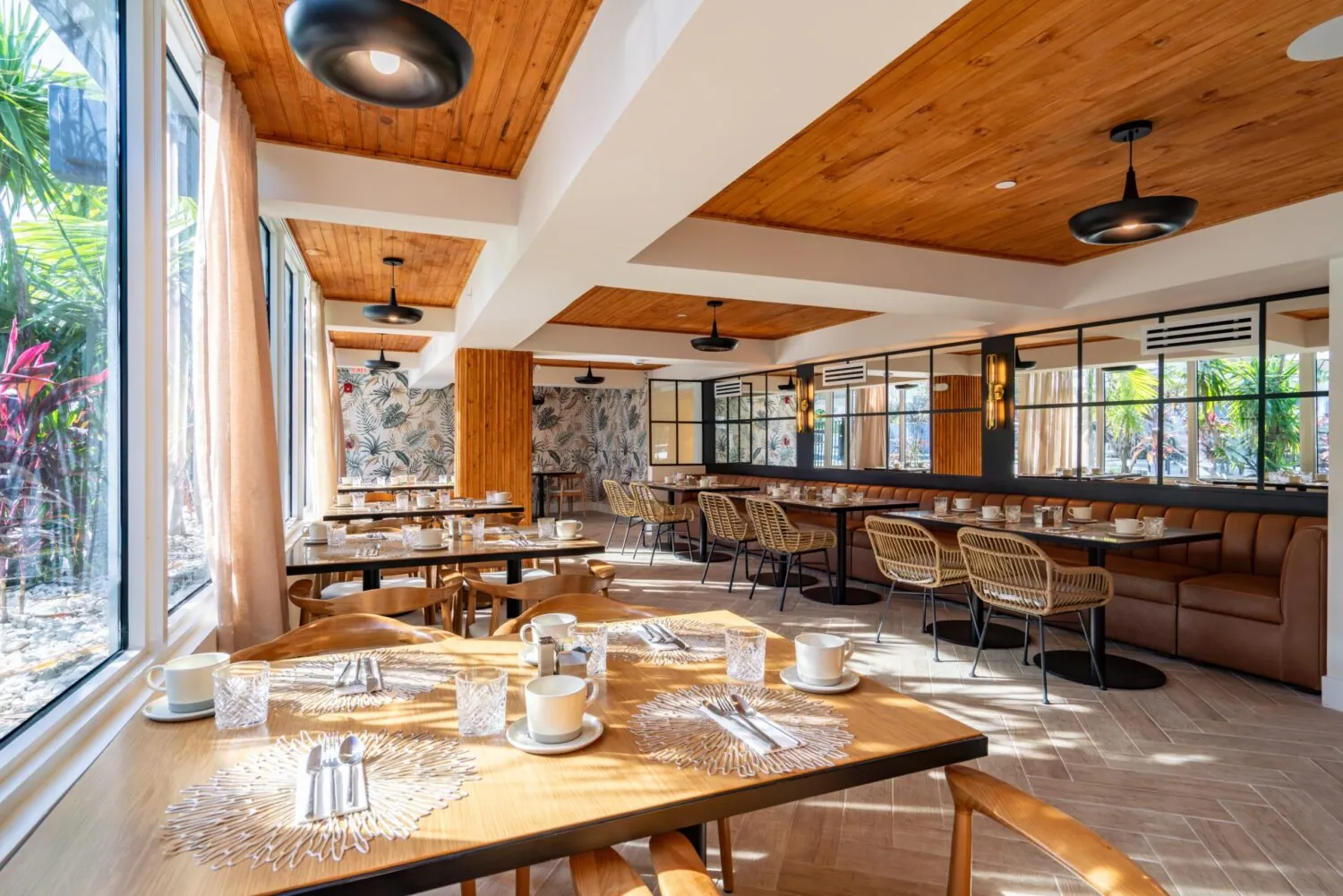 Bright restaurant interior with wood ceilings, bar seating, and set tables