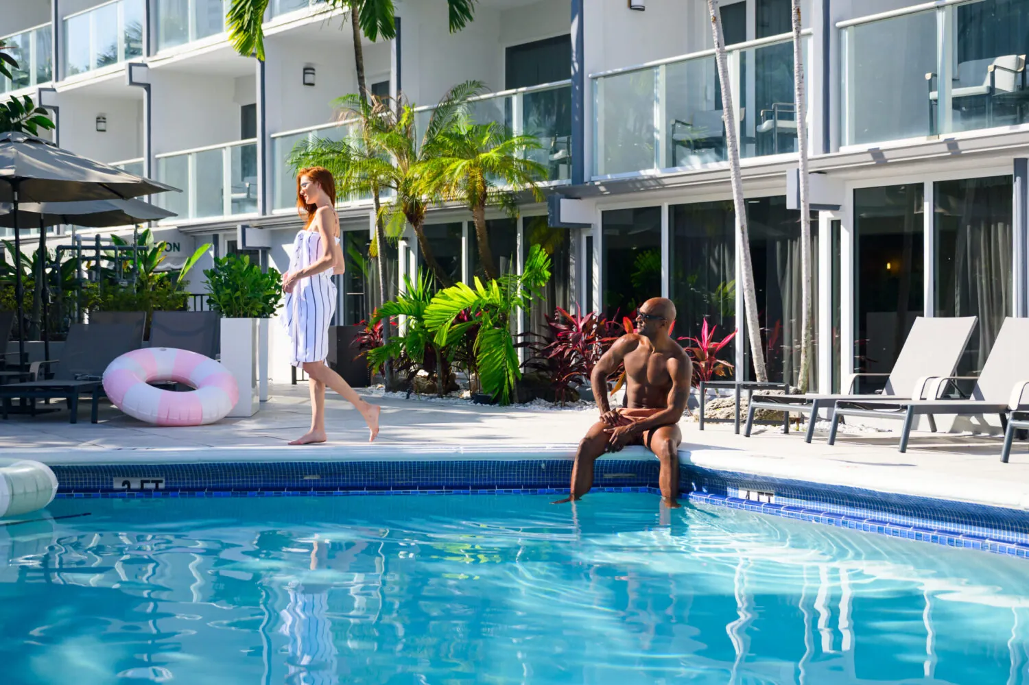 Guests relaxing by an outdoor pool with loungers and inflatable float