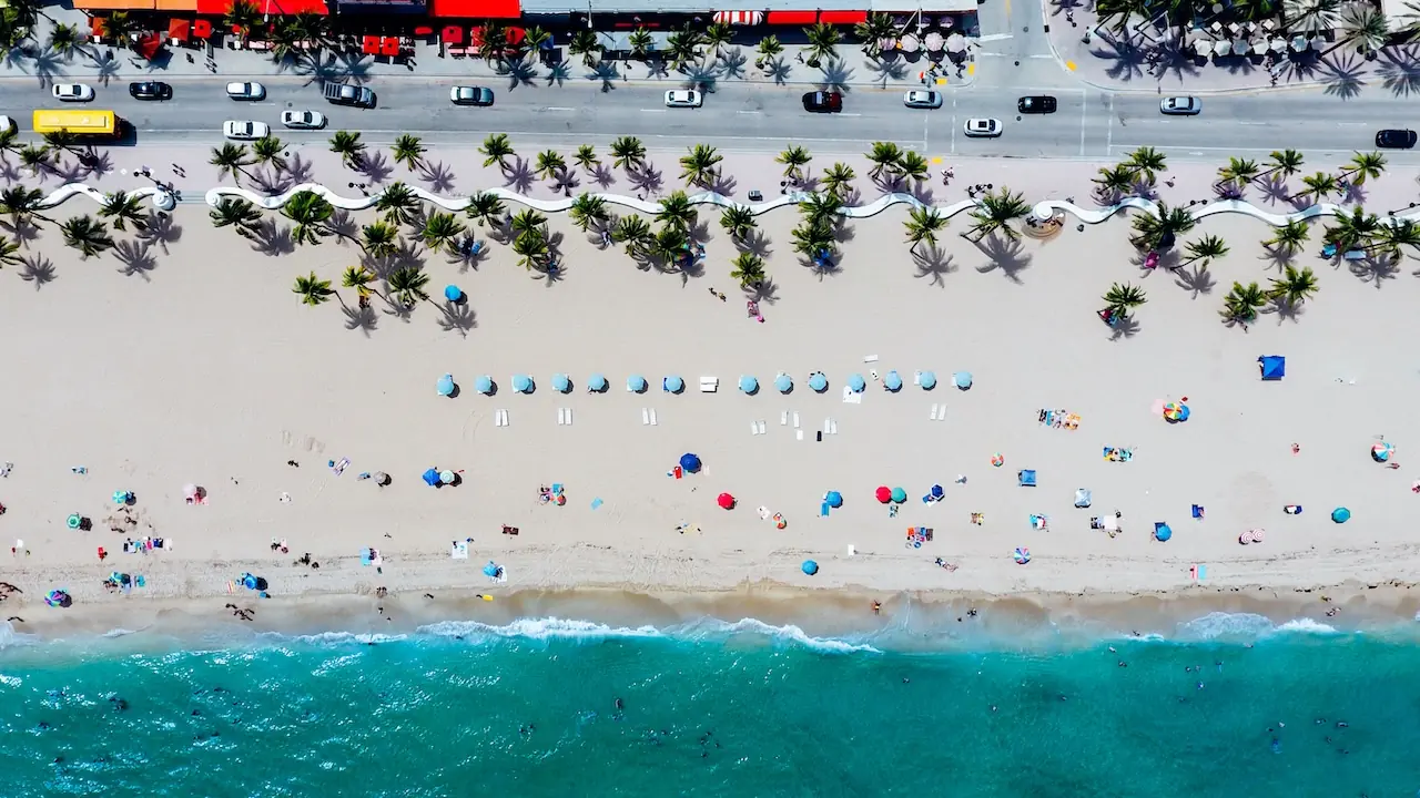 Aerial view of a sandy beach with umbrellas and people along the shoreline
