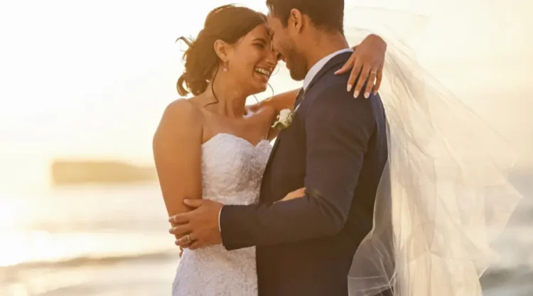 Bride and groom embracing on a beach at sunset