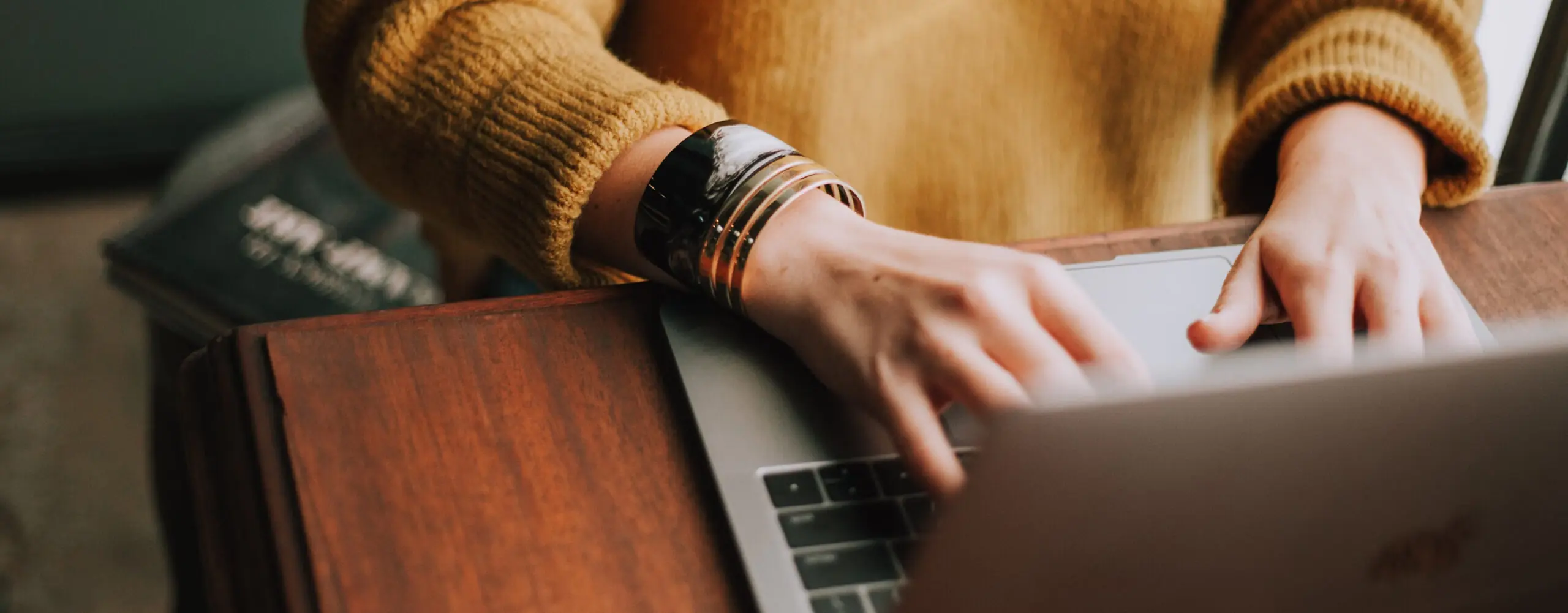 Hands typing on a laptop at a wooden desk